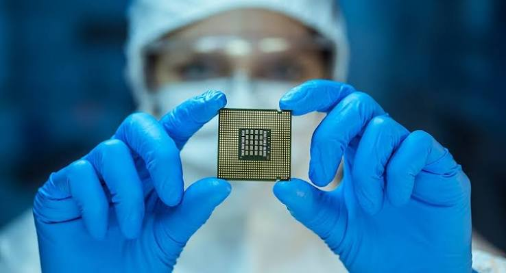 Technician in cleanroom gloves holding an integrated circuit